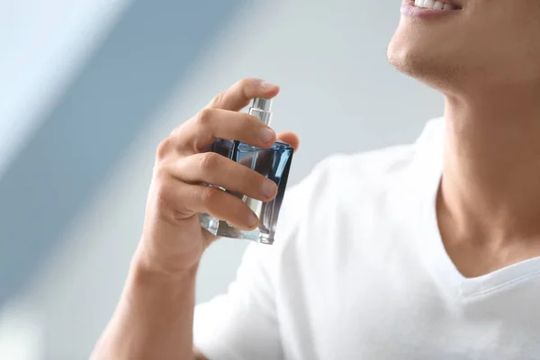 Jeune homme utilisant du parfum à la maison — Photo