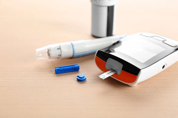 Glucosímetro digital y lápiz lanceta en la mesa. Manejo de la diabetes —  Fotos de Stock