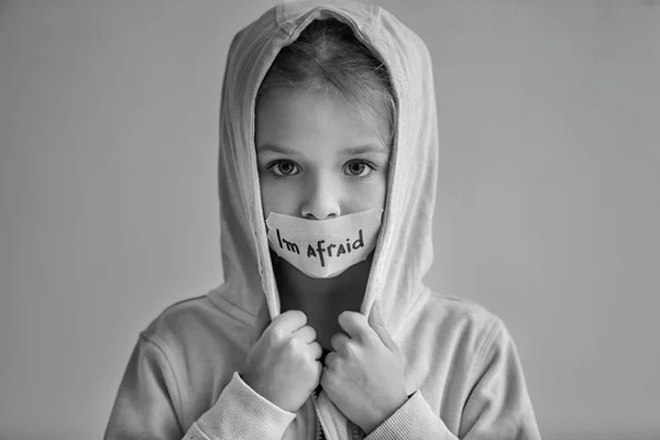 Sad little girl with taped mouth and words 