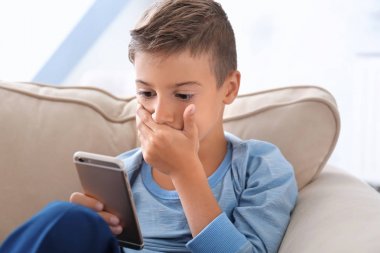 Üzgün küçük çocuk evde smartphone ile