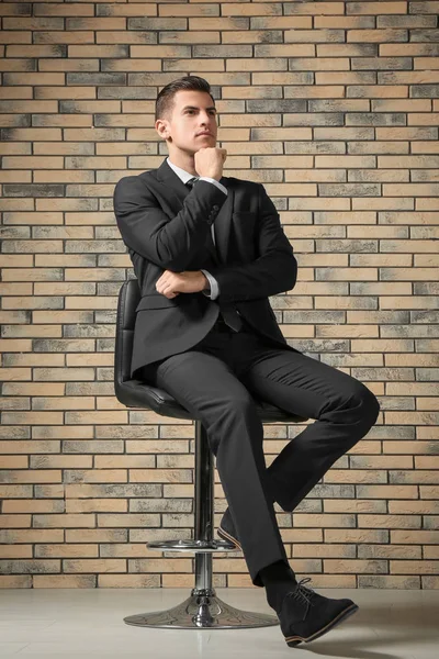 Schöner Mann Eleganten Anzug Sitzt Auf Stuhl Nahe Ziegelwand — Stockfoto