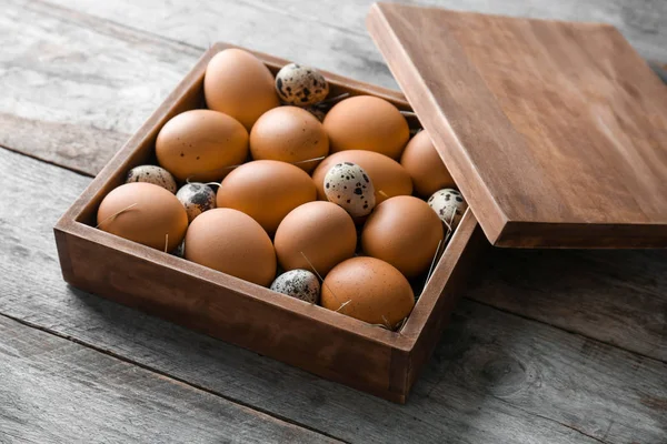 Quail and chicken eggs in box on wooden table