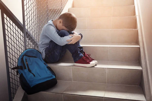 Aufgebrachter kleiner Junge sitzt drinnen auf Treppe — Stockfoto