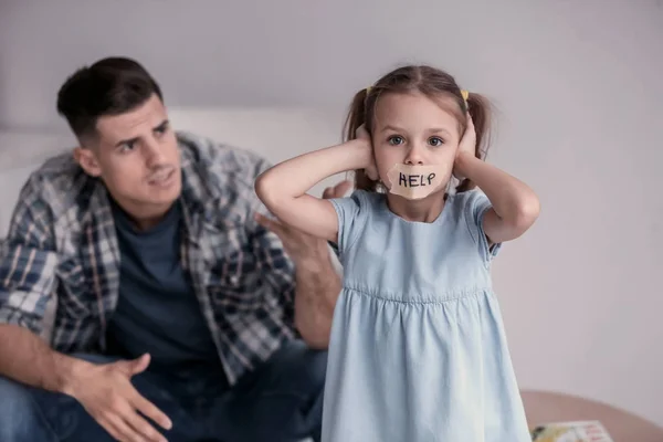 Hombre regañando a su hija con la boca pegada y la palabra "Ayuda" en el interior — Foto de Stock