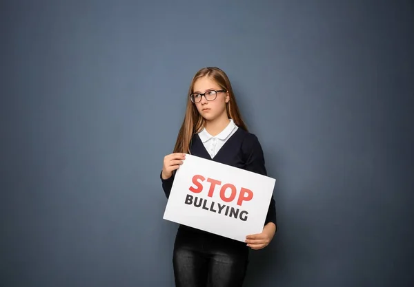 Дівчина-підліток тримає знак "Стоп знущання" на кольоровому фоні — стокове фото