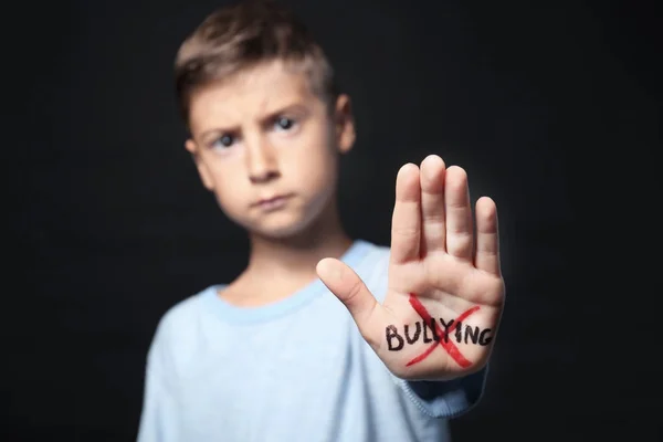 Little boy with crossed word "Bullying" on his hand against black background — Stock Photo, Image