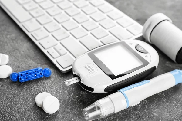 Digital glucometer and lancet pen near computer keyboard on table. Diabetes management — Stock Photo, Image
