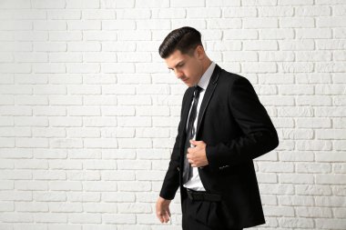 Yakışıklı adam beyaz tuğla duvar yakınındaki şık elbiseli