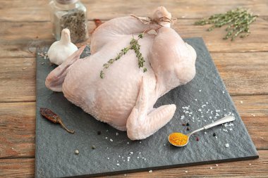 Taze bütün tavuk, kekik ve baharat ahşap masa üzerinde arduvaz levha