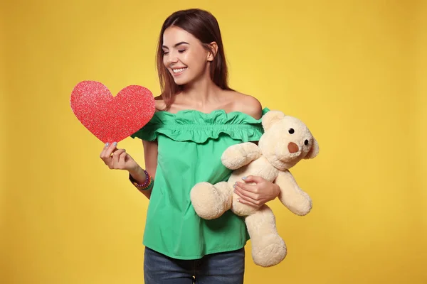 Женщина с бумажным сердцем и игрушечным медведем — стоковое фото