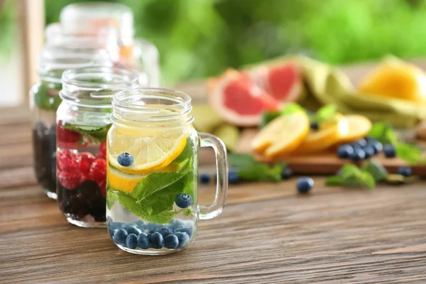 Einmachgläser Mit Wasser Obst Und Beeren Auf Holztisch — Stockfoto