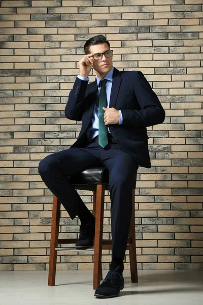 Schöner Mann Eleganten Anzug Sitzt Auf Stuhl Nahe Ziegelwand — Stockfoto