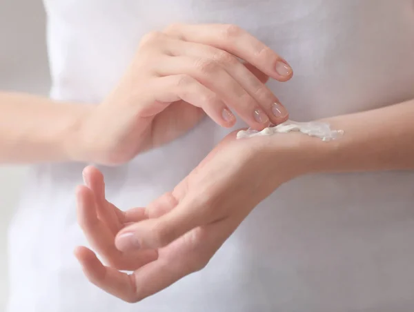 Mujer joven aplicando crema de manos, primer plano —  Fotos de Stock