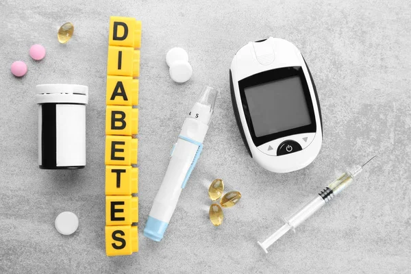 Composición con la palabra "Diabetes", medicamentos y glucosímetro digital sobre fondo gris — Foto de Stock