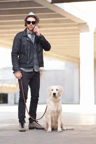 Guapo joven hipster con perro al aire libre — Foto de Stock
