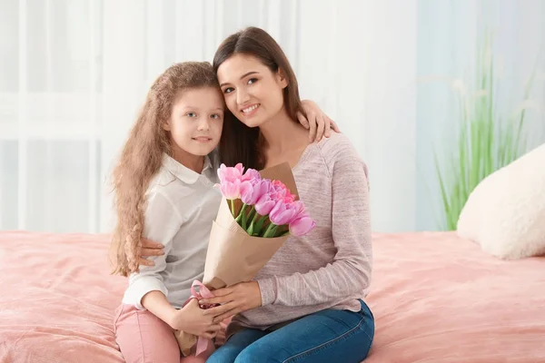 Młoda kobieta i jej córka z bukiet tulipanów w pomieszczeniu. Celebracja dzień matki — Zdjęcie stockowe