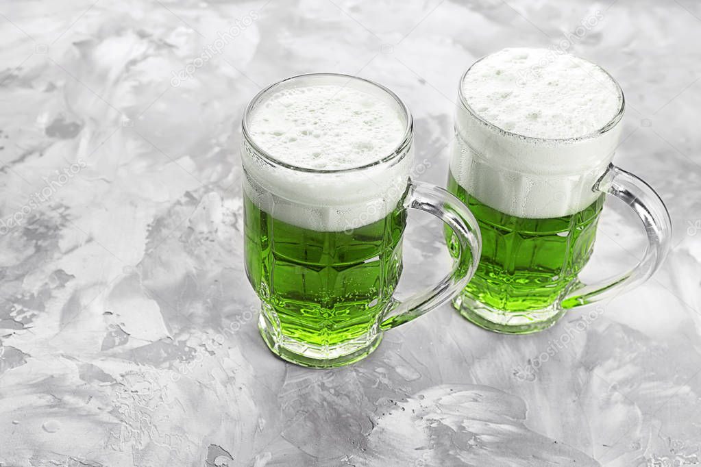 Glasses of green beer on grey background. Saint Patrick's day celebration