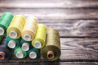 Ahşap arka plan üzerinde renkli dikiş ipliği kümesi