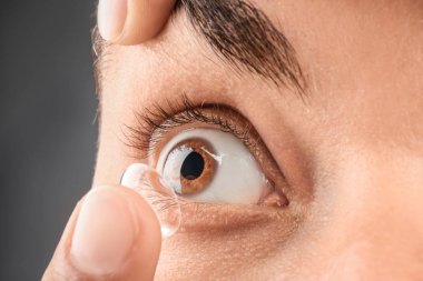 Koyarak Kontakt lens koyu arka plan, closeup üzerinde onun gözünde genç adam