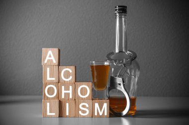 Farklı güçlü içecekler, kelepçe ve küpleri ile kelime alkolizm masada