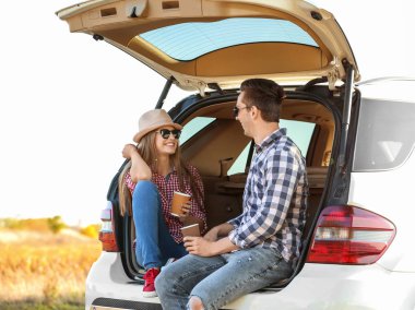 Kahve araba gövde ile oturan güzel genç Çift