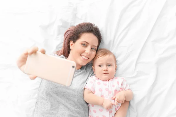 Jovem Mãe Tomando Selfie Com Seu Bebê Bonito Cama — Fotografia de Stock