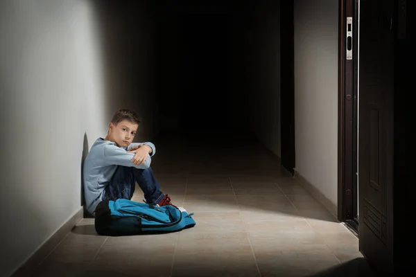 Upset little boy sitting in hallway — Stock Photo, Image