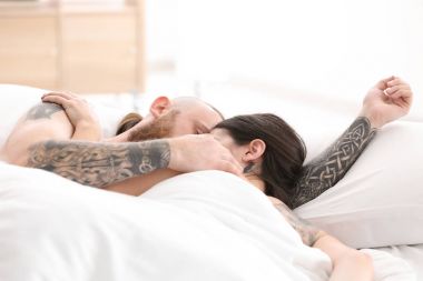 Evde yatakta dövmeli çekici genç Çift