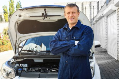 Auto mechanic standing near car outdoors clipart