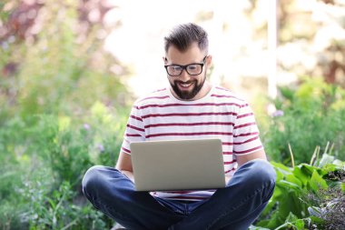 Genç blogger parkta dizüstü bilgisayar kullanarak