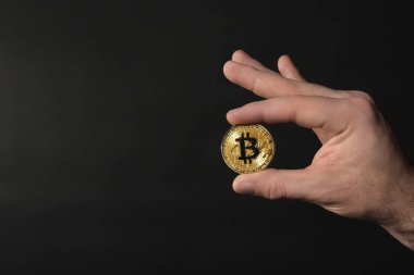 Erkek el ile koyu zemin üzerine altın bitcoin