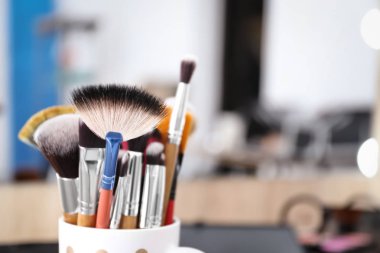 Fırçalar ile fincan bulanık arka plan üzerinde profesyonel makyaj sanatçısı