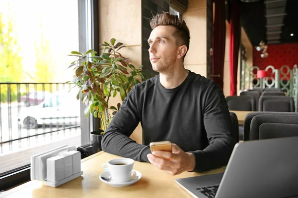 Młody człowiek z laptopem w kawiarni — Zdjęcie stockowe