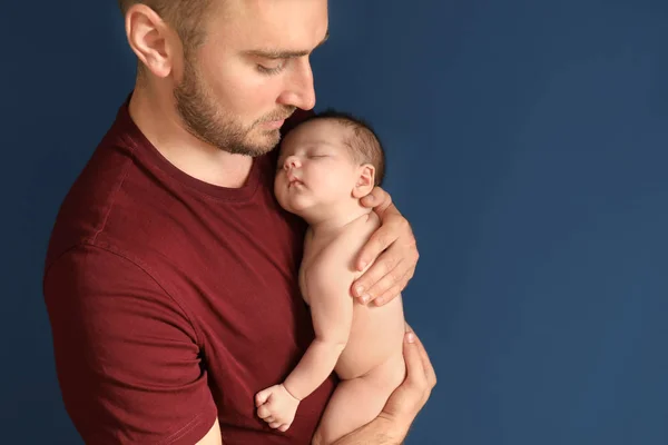 Père avec mignon petit bébé sur fond de couleur sombre — Photo