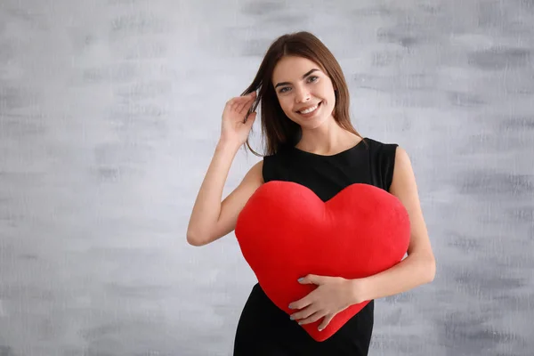 Kalp şeklinde yastık ile genç kadın — Stok fotoğraf