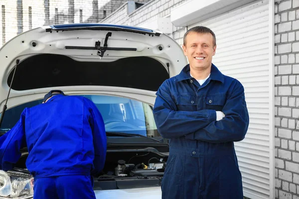 自動車整備士と彼の同僚は 屋外で車の修理 — ストック写真