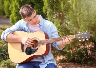 Parkta akustik gitar çalan yetenekli genç.