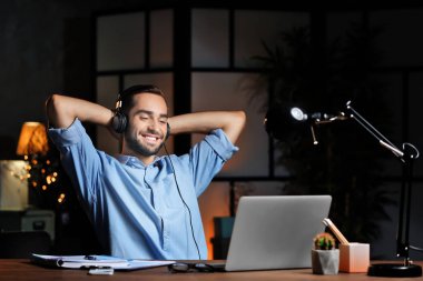 Dizüstü bilgisayar kullanarak ve geceleri Office müzik dinlemek genç adam