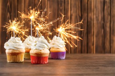 Ahşap arka plan karşı masada havai fişekleri ile doğum günü cupcakes