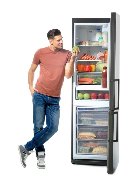 Uomo in piedi vicino frigorifero pieno di prodotti — Foto Stock