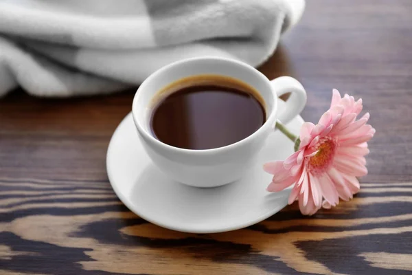 Cup of coffee with flower on wooden background