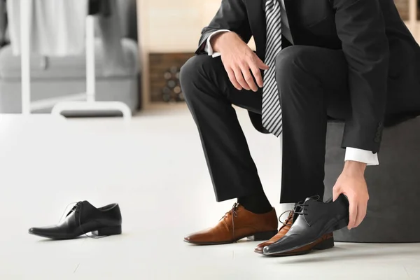 Young man trying on shoes in shop