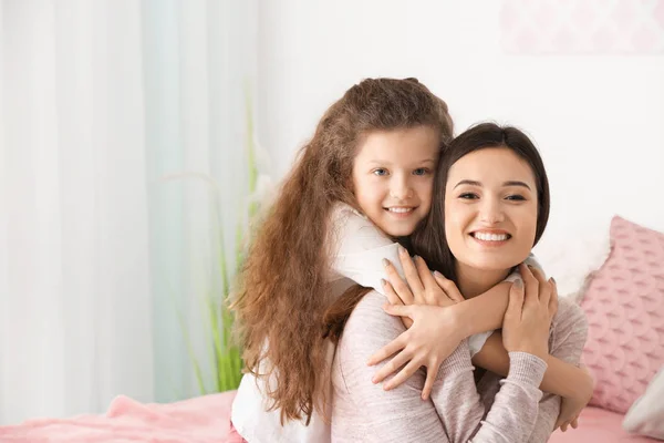 Niña abrazando a su madre en el interior — Foto de Stock