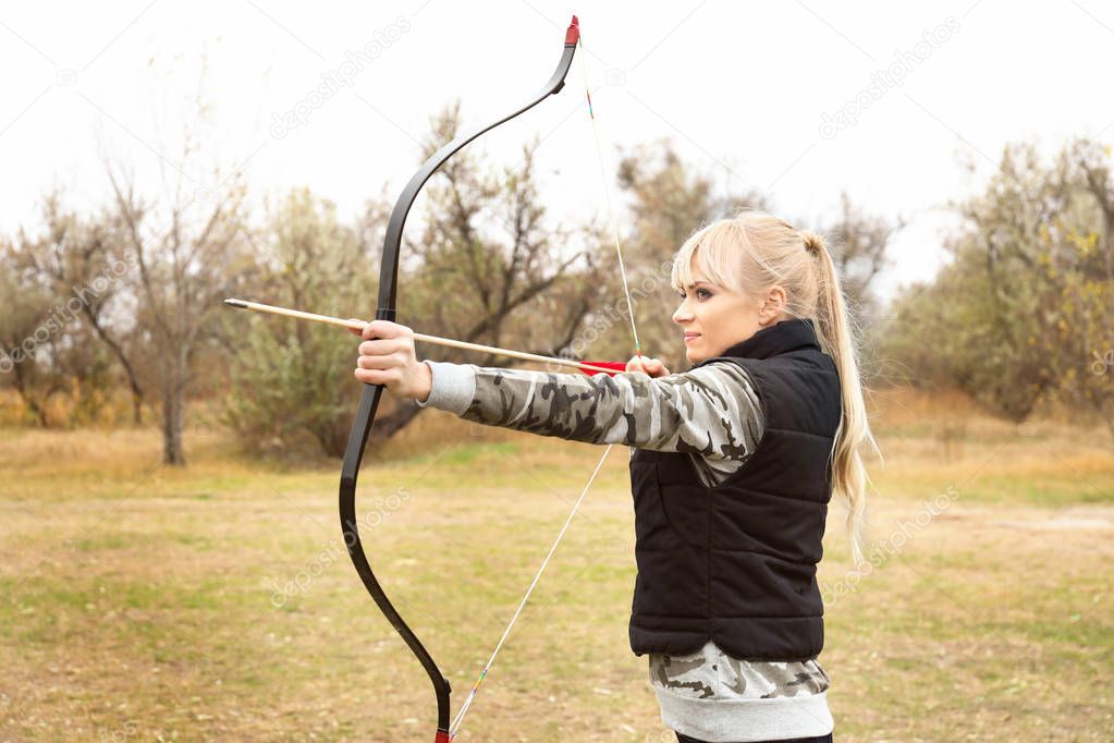 Attractive woman practicing archery outdoors