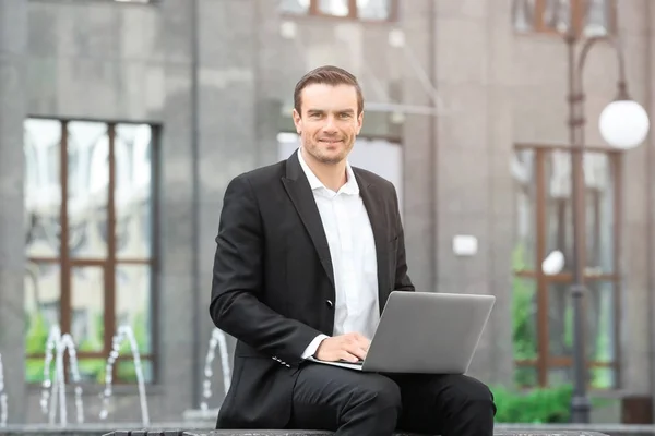 Homme assis sur un banc à l'extérieur et utilisant un ordinateur portable — Photo