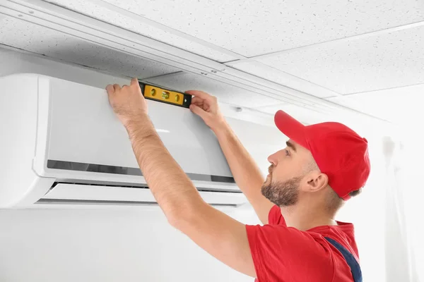 Técnico masculino instalando ar condicionado dentro de casa — Fotografia de Stock