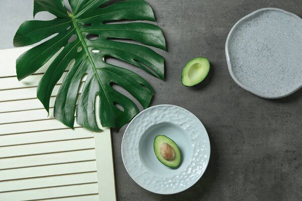 Composition with ceramic plates and avocado on grey background