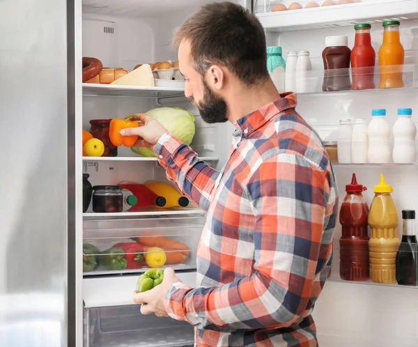 Красивый Человек Берет Свежий Перец Холодильника — стоковое фото