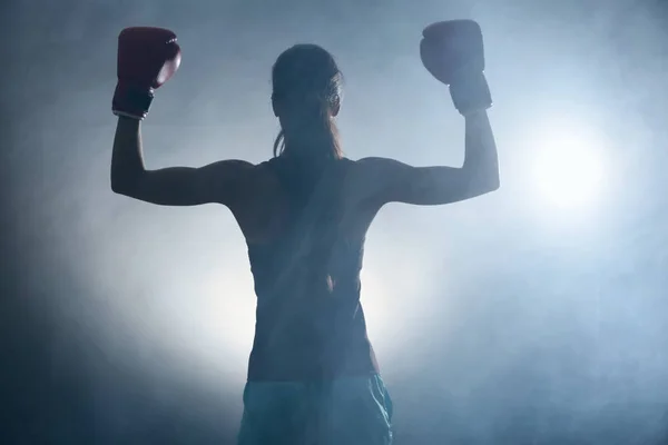 Silhouette of strong boxer woman on dark background