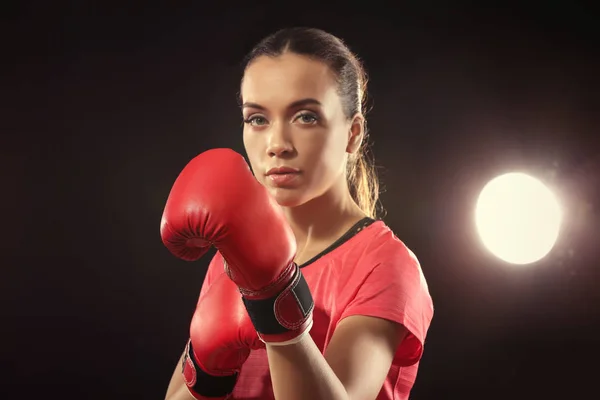 Strong woman in boxing gloves on black background